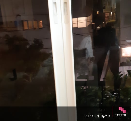 תריסים לבנים על חלון זכוכית בלילה